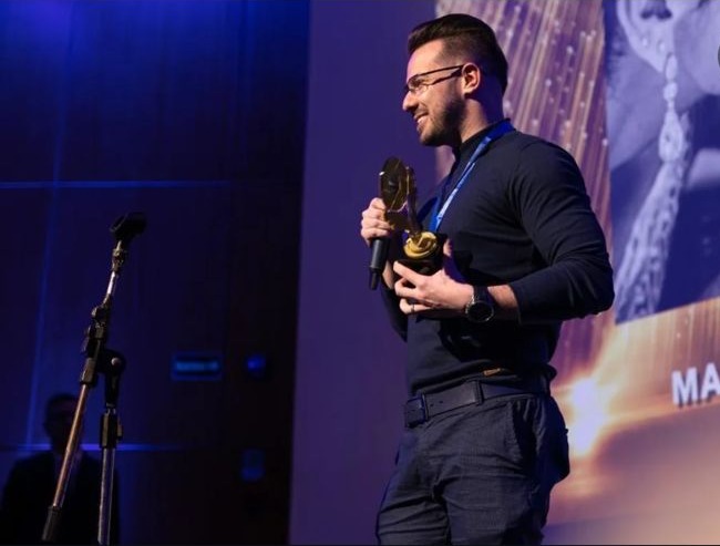 Fotógrafo segurando troféu no palco